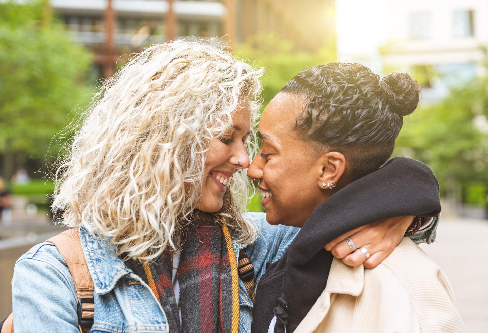 Happy multiracial girlfriends in love embracing and cuddling - Lesbian couple, millennials women, girls in London living happy lifestyle - LGBTQ concept with mixed race beautiful couple