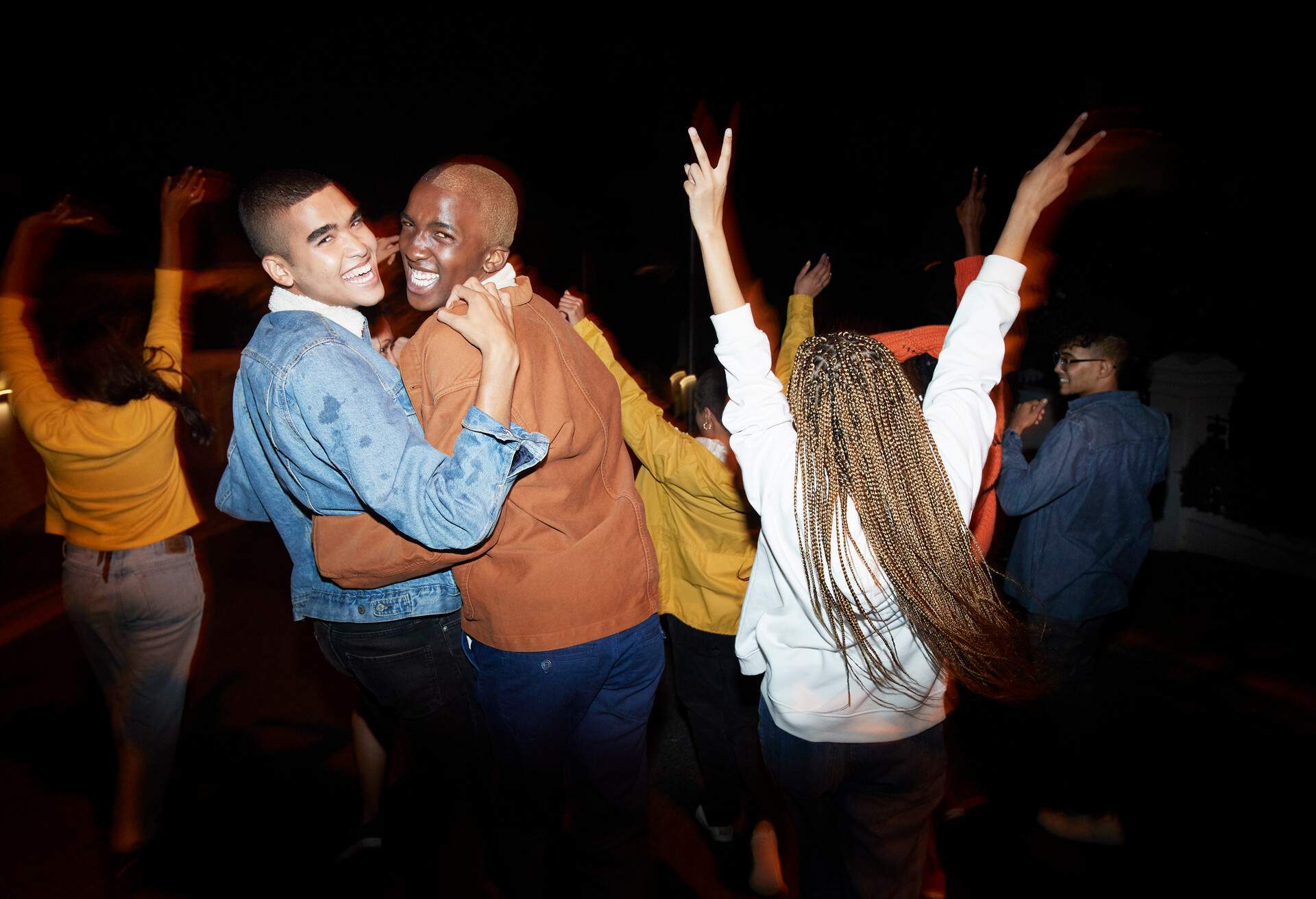 Portrait of cheerful young men dancing with multi-ethnic friends at night
