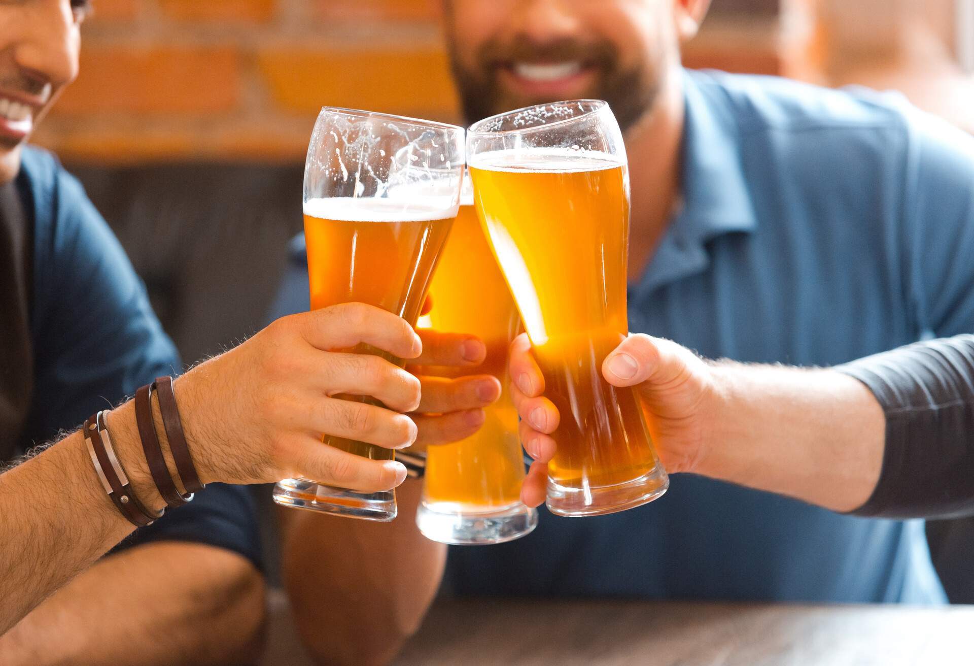 Three men drinking beer in the pub, toasting with beer glasses.