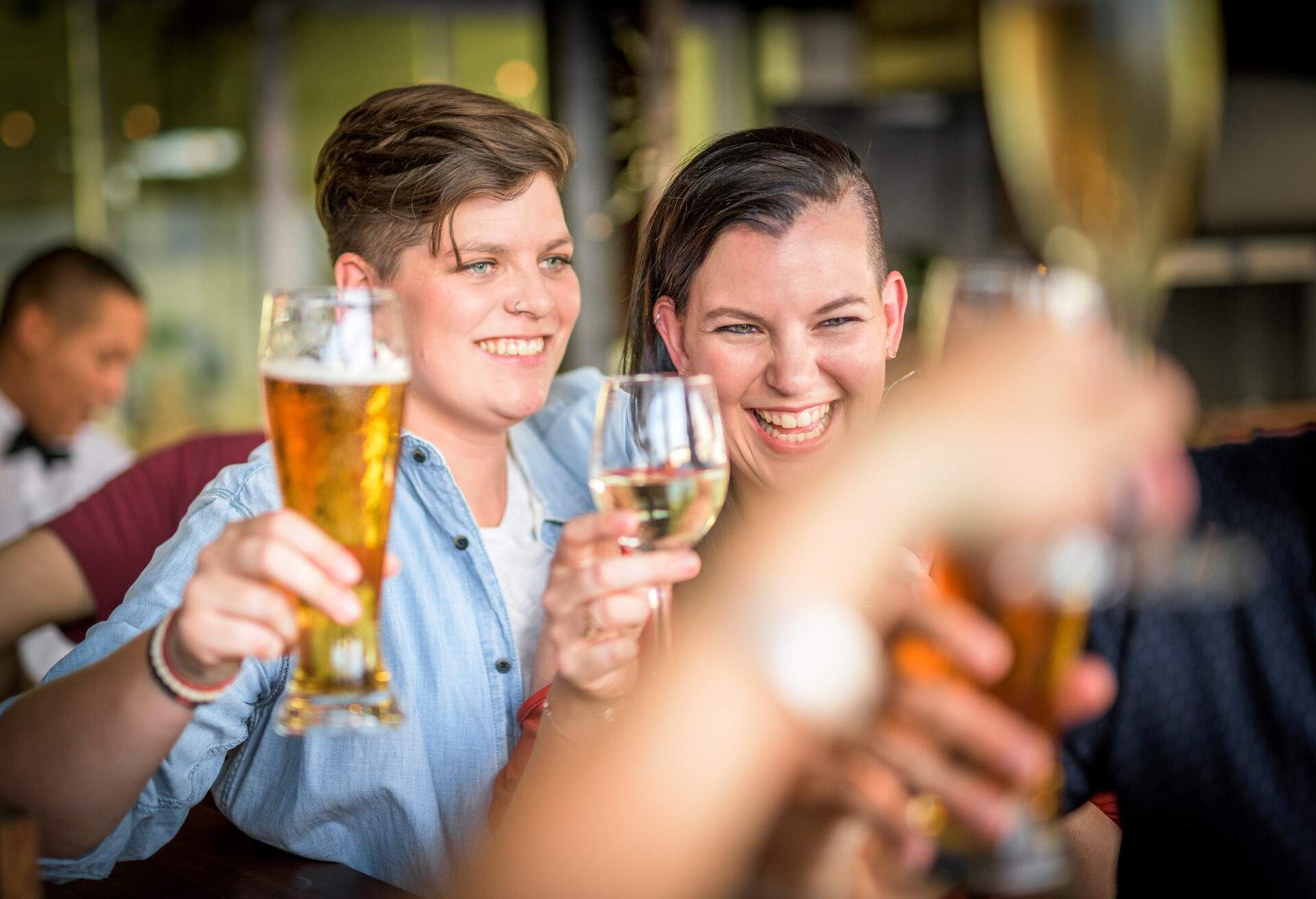 Smiling lesbian couple toasting drinks. Young women are spending leisure time at restaurant. They are enjoying at bar.