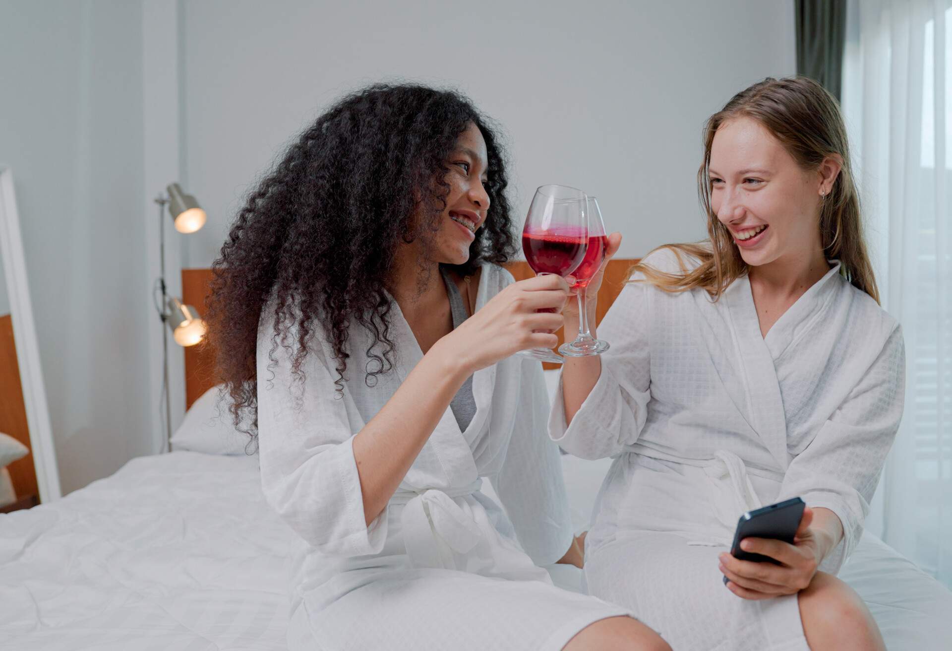 A young lesbian couple laughing at funny stories they tell each other while relaxing in a luxury hotel. 