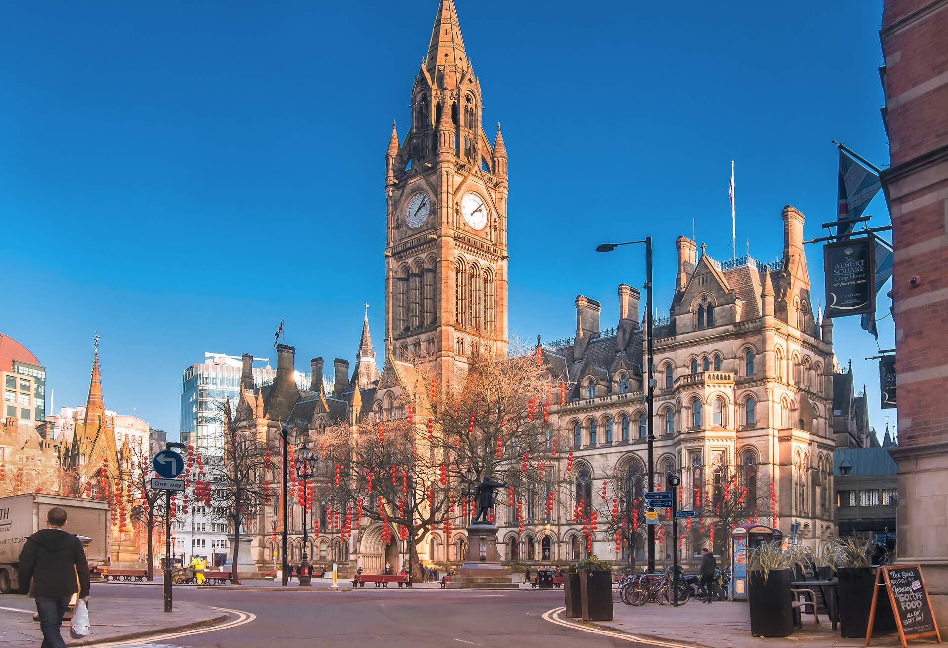 Leafless trees decorated with red lanterns in front of the Manchester Town Hall.