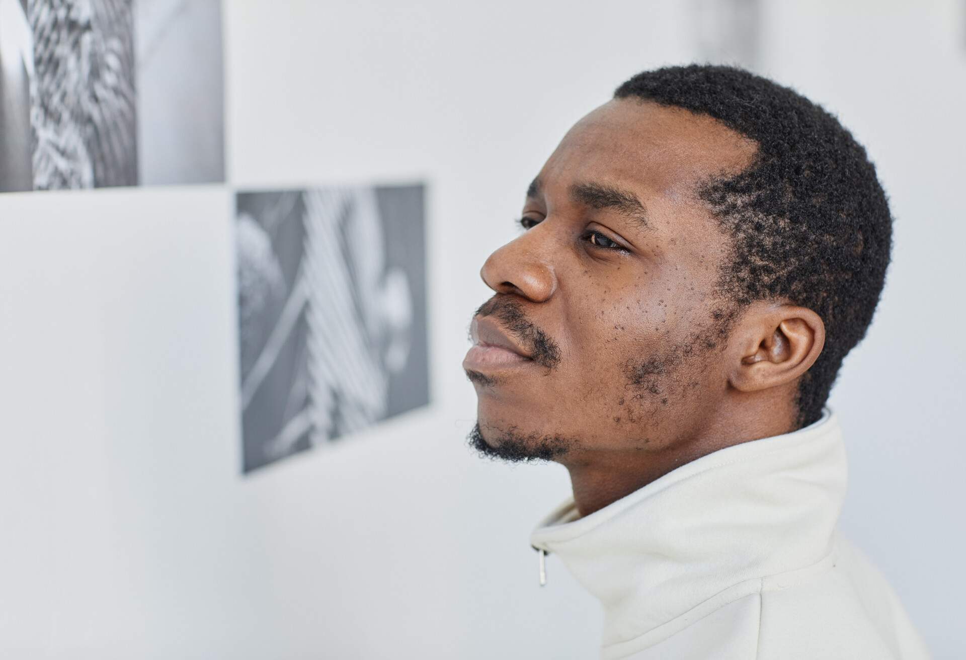 A man checking out the pictures hanging on the wall of a museum.