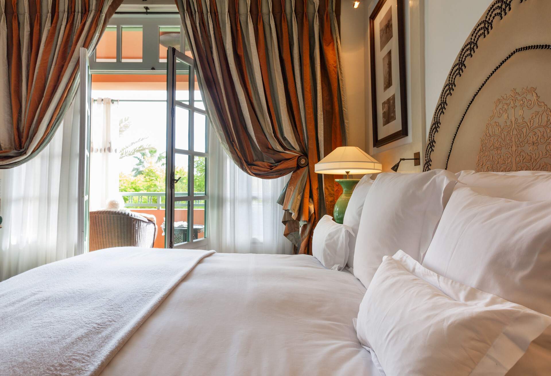 A lovely bedroom with crisp white bedding and striped drapes.