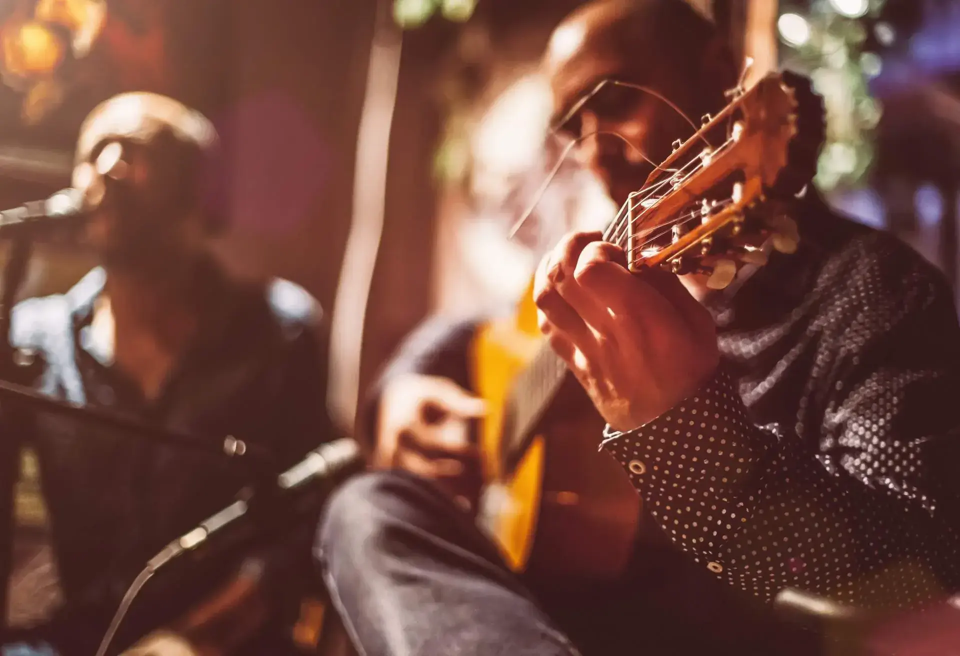 Two male musicians on a stage performing traditional flamenco music.