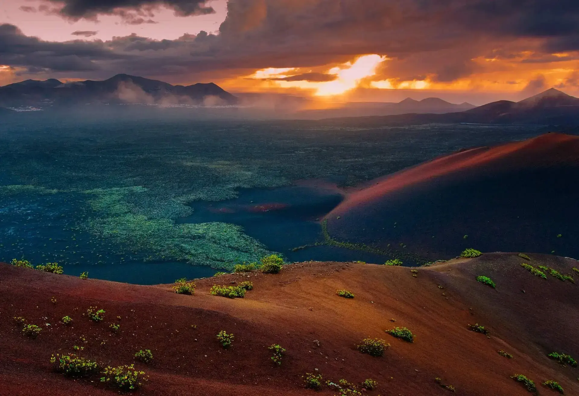 Daylight falls on reddish slopes of volcanoes of Timanfaya National Park in Lanzarote.