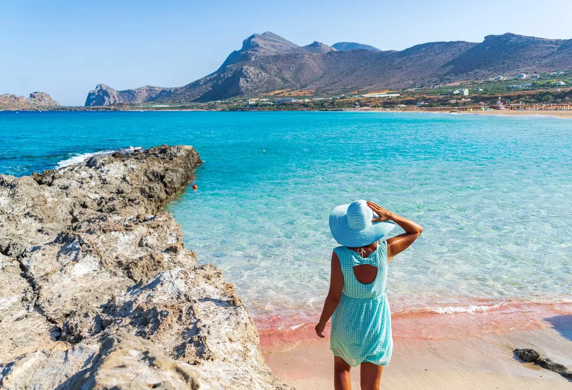 DEST_GREECE_CRETE_FALASARNA_BEACH_WOMAN_PINK_SAND_GettyImages-1338743669