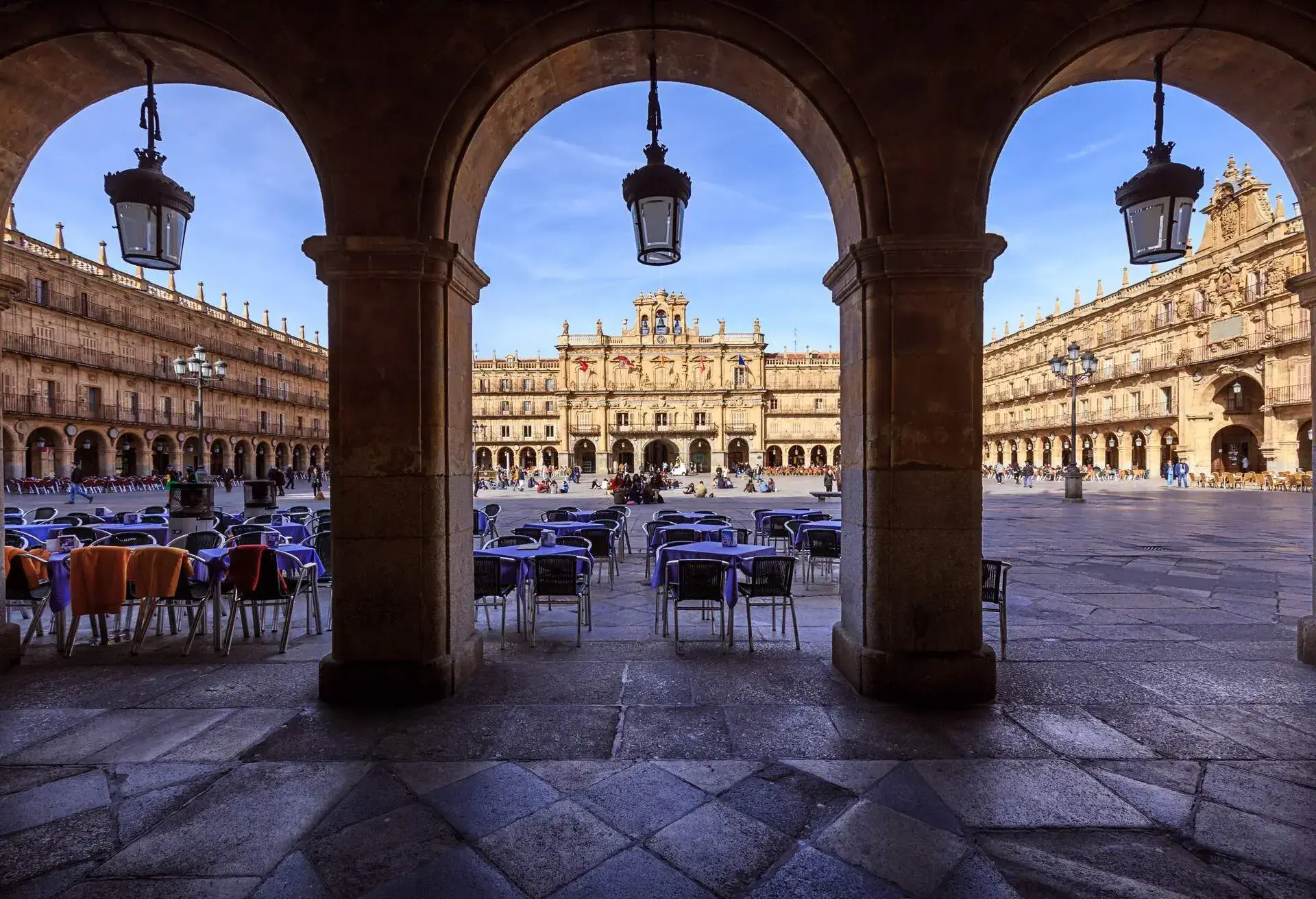 Front view of the main square of Salamanca with the town hall in the background and three arches in the foreground. During a sunny day.