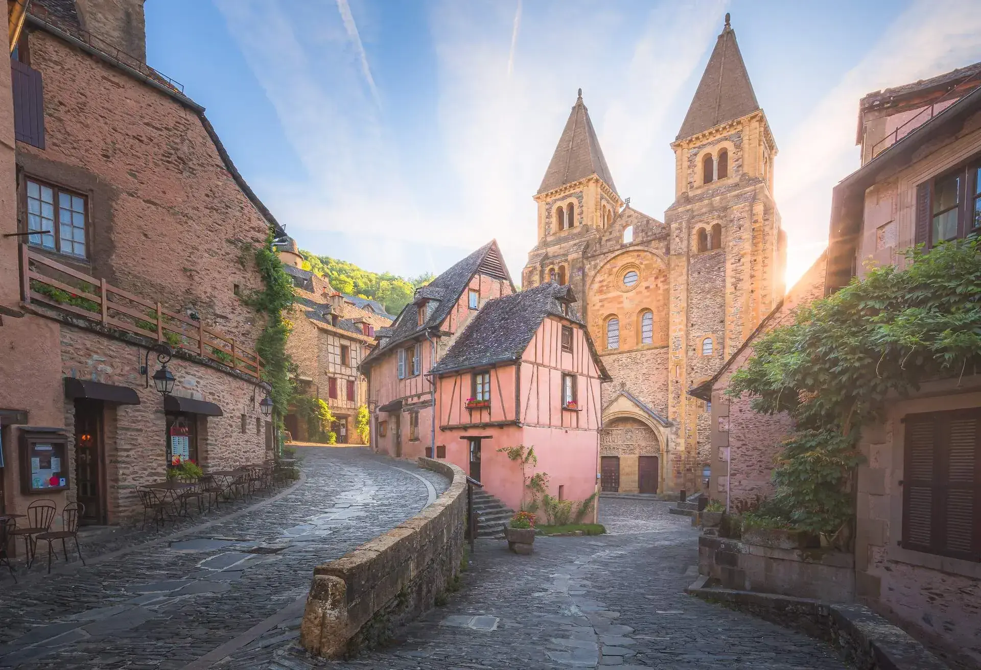 The quaint and charming town centre of the medieval French village Conques, Aveyron and Abbey Church of Sainte-Foy at sunset or sunrise in Occitanie, France.