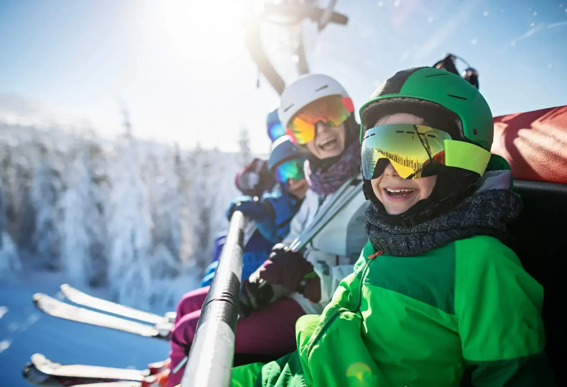 Mother skiing with kids on a sunny winter day. Family is sitting on chairlift cheering at the camera...Nikon D850