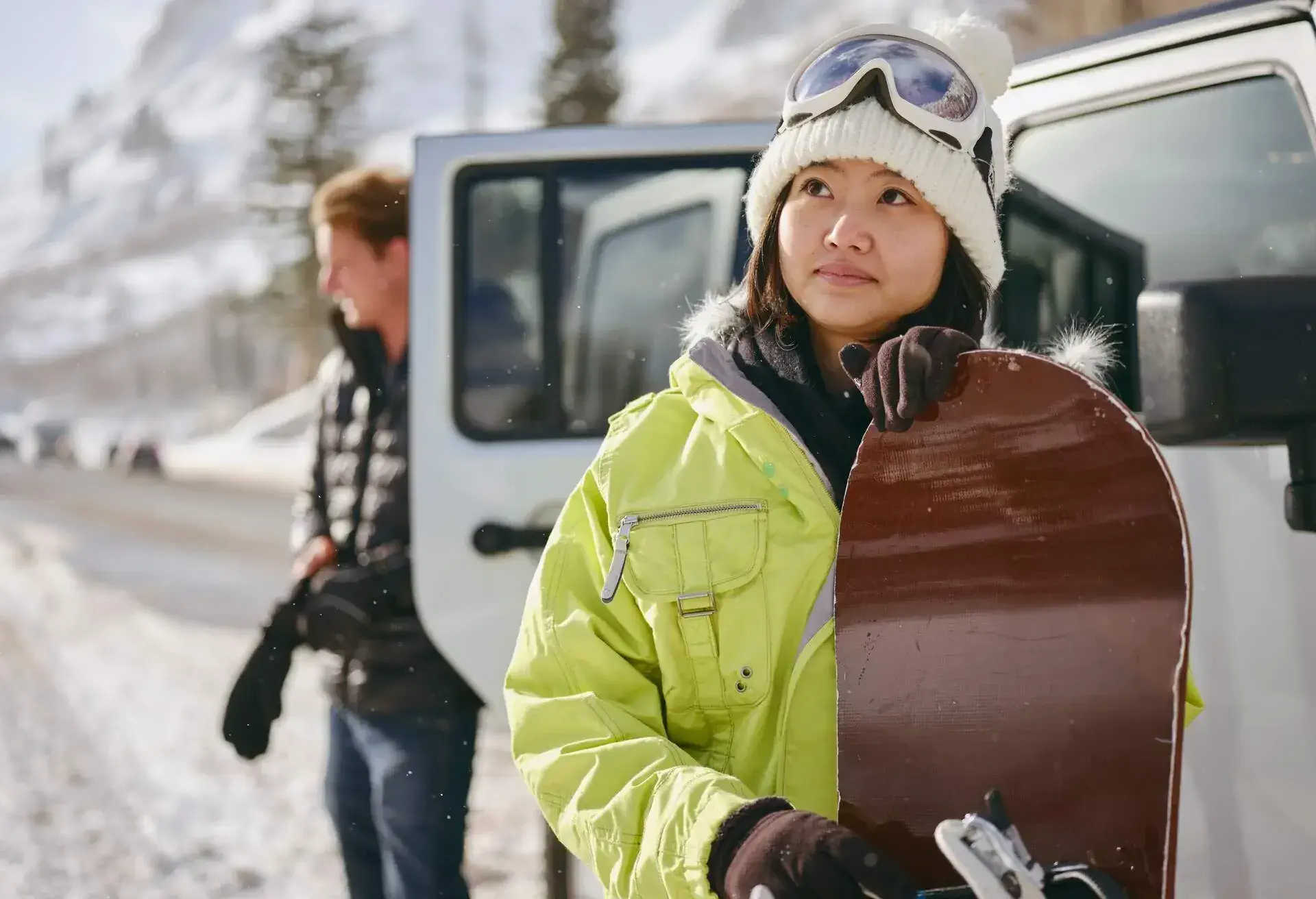 Young adults enjoying a winter outing, driving their vehicles in the mountains.