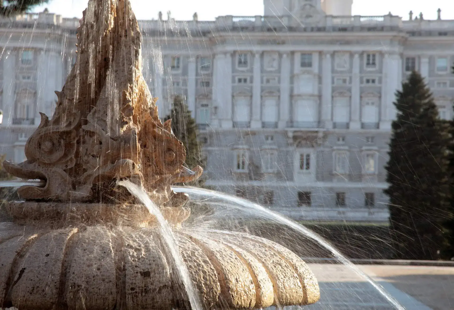 water flowing from a fountain outside the Palacio Real in Madrid, Spain. Shot on long exposure to show flow of water. Late afternoon sunlight, the focus is on the water with the Palace in soft focus