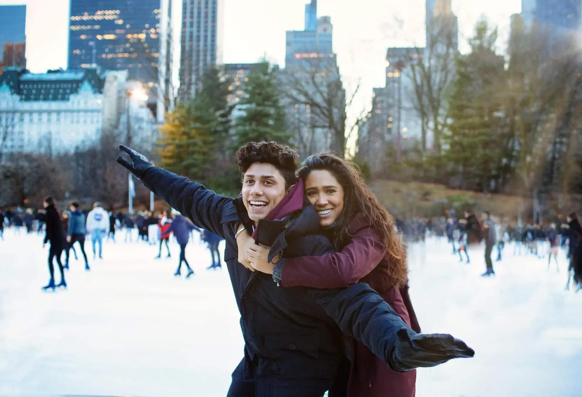 Portrait of a happy young couple smiling, hugging and having fun while ice skating outside in Central Park, NYC
