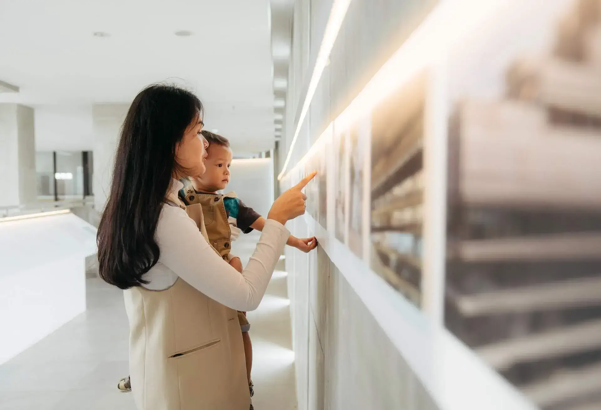Asian women watching the exhibition with her baby in art gallery