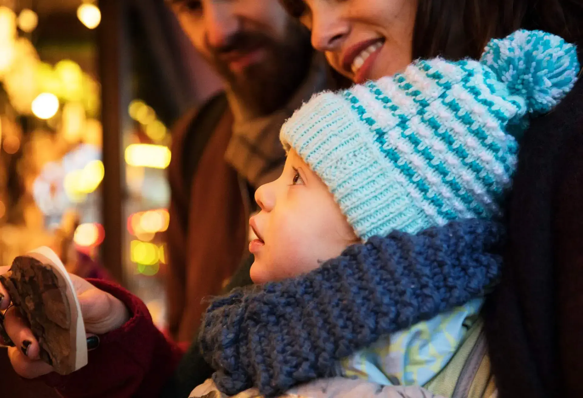 A couple with a young child looking at an ornament at a market stall.