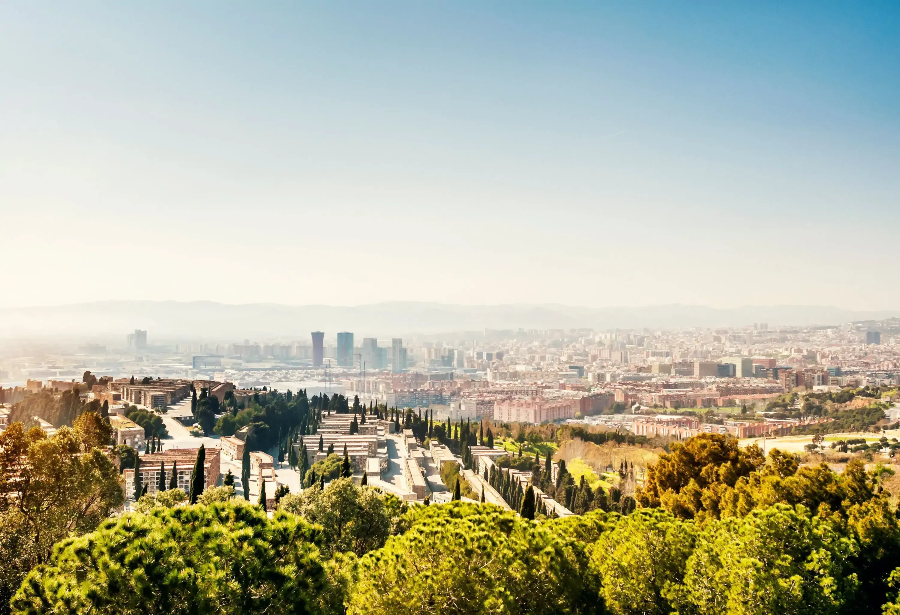 Cemetery perched on a hilltop with a view of a city's metropolitan setting.