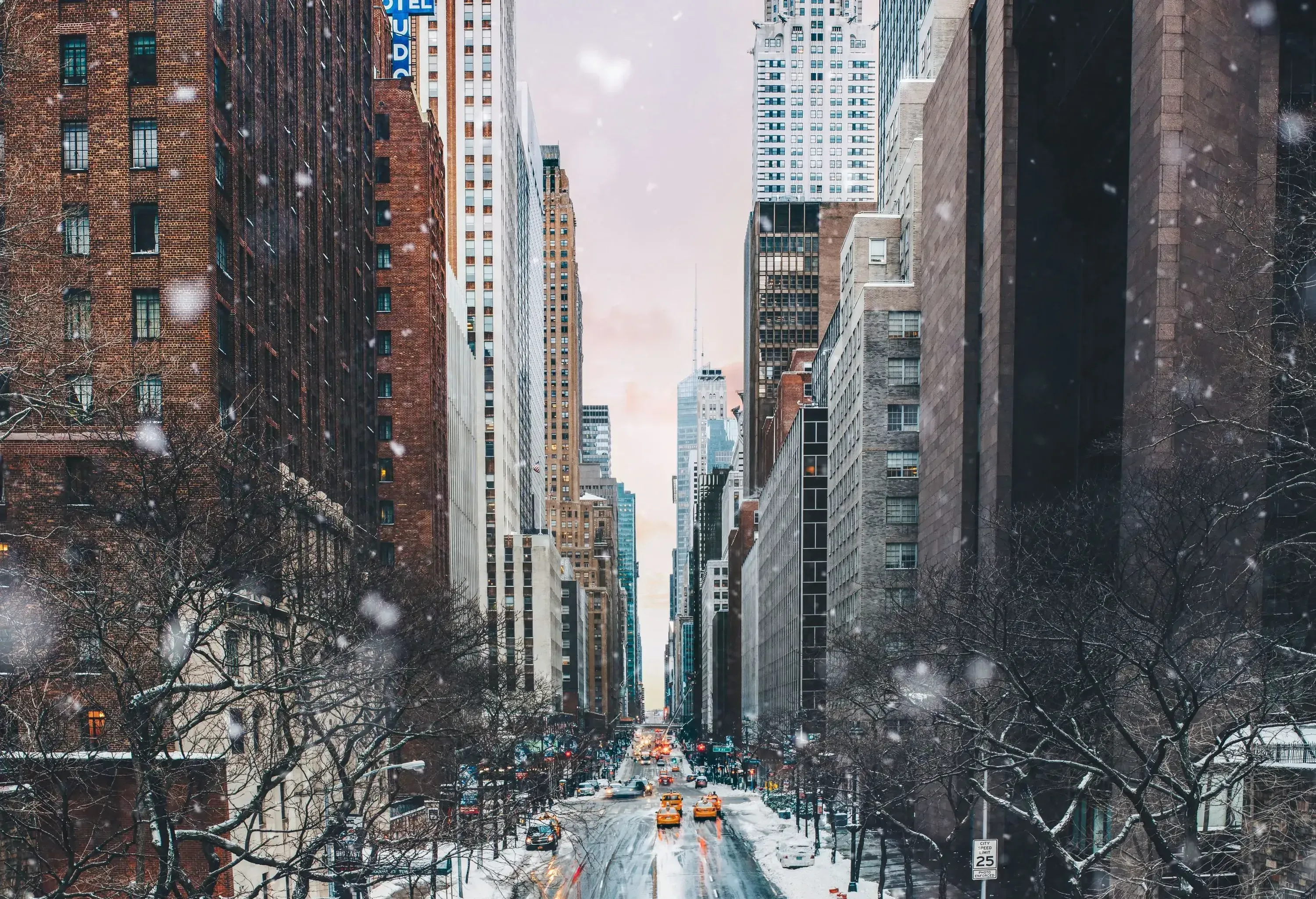 A snow-covered street with a long road, lined by tall buildings on both sides.